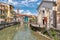 View of the Sacred Heart Oratory on the canal and Sant Ambrogio church in the historic center of Omegna, Piedmont, Italy