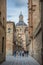 View of a Salamanca downtown medieval street with student girls walking and baroque iconic dome copula at the La Clerecia building