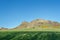 View of Salisbury crags on Holyrood Park with green spaces, tourists walking and looking, blue sky on background, in Edinburgh