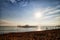 View from sand beach to water of sea, waves, pier and black silhouette of person in a nice day or evening with blues sky, bright