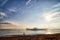 View from sand beach to water of sea, waves, pier and black silhouette of person in a nice day or evening with blues sky, bright