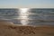 View of a sandy beach and gentle ocean under a blue sky with a sun star and text The Baltic Sea written in the sand