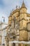 View of the Santa Cruz Monastery front facade, romanesque and gothic style, with tourists on street , a National Monument in