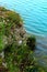 View from Santarelli lakes with a crest of land in greenery, dirt and rocks above the aquamarine waters