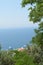 View of the sea coast and the beautiful roofs of the hotels through the framed trees, vertical shot