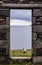 View of sea, pastures and lamb from a stone door of an old ruin