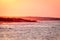 View of the sea and shore against the background of the reddish sky at sunset.