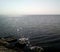 View of the sea from the shore on a sunny day. Calm sea with light ripples on the surface of the water and small waves.