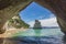 The view of sea side arch passage of Cathedral Cove with solitary rock stack called Te Hoho in Coromandel, New Zealand.
