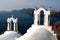 View of sea surface through traditional Greek white church arch with cross and bells in Oia village of Cyclades Island, Santorini,