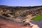 View on secluded deep green lake Lago verde in lagoon surrounded by impressive cliffs - El Golfo, Lanzarote