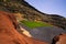 View on secluded deep green lake Lago verde in lagoon surrounded by impressive cliffs - El Golfo, Lanzarote