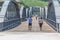 View of a senior couple of tourists on backs, strolling through the metallic bridge of the city of Peso Regua