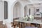 a view of a set dining table in a chic expensive bright interior of a huge living room in a historic mansion with arched arches,