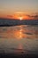 View of the setting sun shining on the Sea and reflected on the beach, clouds with sun-shining edges. Landscape