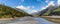 View of shallow Skagway River and Skagway airport in Alaska. Blue cloudy sky and mountain peaks in the background