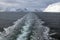 View of ship`s wake with snow covered mountains in background