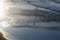 View of the shore of the ocean at low tide. Reflection of the sun in the ocean, surfers in the water.