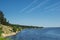 View of the shore of a picturesque river and traces of the plane in the sky