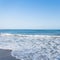 View of from the shore of on a restless sea with of white foam with sunny sky. Summer paradise beach in Spain. Summer seascape.