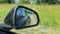 View into the side mirror of a black sports car while driving