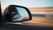 View in side mirror car that is driving fast on highway in sunset light.