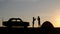 A view of a silhouette of a loving couple, who clap their hands against the sunset