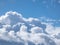 View of sky with fluffy white clouds in a sunny day. Background of dark sky sunlit with beautiful white clouds
