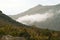 The view from the slope of the mountain above the clouds to the opposite slope of the gorge in the atmospheric haze with a creepin