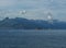 View of small rocky island, Santa Maria Navarrese village marina and limestone cliffs of Gulf of Orosei, viewed over sea