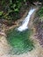 View of a small rushing crystal clear waterfall in the middle of a forest