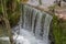 View of small waterfall on river with detail of water foam, rocks and river vegetation