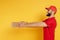 View of smiling bearded delivery man in red uniform giving pizza boxes on yellow