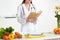 View of smiling dietitian in white coat reading book at workplace