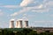 View of smoking chimneys of nuclear power plant, power lines and forest, under blue sky with clouds