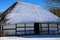 View on snow covered half timbered farm house with reed roof against blue sky - Schwaam, Germany focus on roof