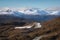 view of snowy peaks with rugged terrain from winding mountain road