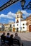View of the Socorro Parish church with people sitting on a bench in the foreground, Ronda, Spain.