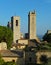 View of some of the towers of San Gimignano, Italy against blue sky, taken from the Parco della Rocca full of trees