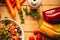 A view of a spelled dish on wooden background with some ingredients around: carrots, peppers, tomatos, parsley and oil