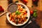 A view of a spelled dish on wooden background with some ingredients around: carrots, peppers, tomatos, parsley and oil