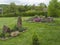 View on spring garden with oval flower bed with green herbs with big sandstone rock and blooming rock garden on