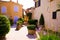 View on square of mediterranean village decorated with pots of flowers and green plants in bright sunshine - Gassin, Cote dÂ´Azur