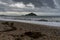 View of the St. Michael`s Mount tidal island in Mount`s Bay in Cornwall with waves crashing on a rocky beach