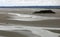 View from St. Michel mountain in France during low tide and groups of tourists in the middle of the beach