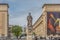 View of the statue of D. Dinis, in the square of the University of Coimbra, surrounding buildings, people and vehicles, cloudy sky