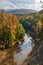 View from steep bank of Afips river at sunset. Scenic sunny golden autumn vertical landscape of Caucasus Mountain forest at