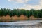 View of the steep river Bank on a Sunny day. Hilly river Bank overgrown with trees