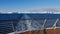 View from the stern of a cruise ship with the vessel\\\'s wake in the arctic ocean and snow-covered mountains near Hammerfest.