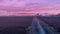 View from the stern of cruise ship with the vessel\\\'s wake in arctic sea, snow-covered mountains and purple colored sky.